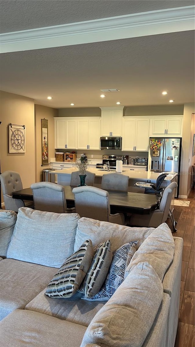 living room with ornamental molding, dark wood-type flooring, and a textured ceiling