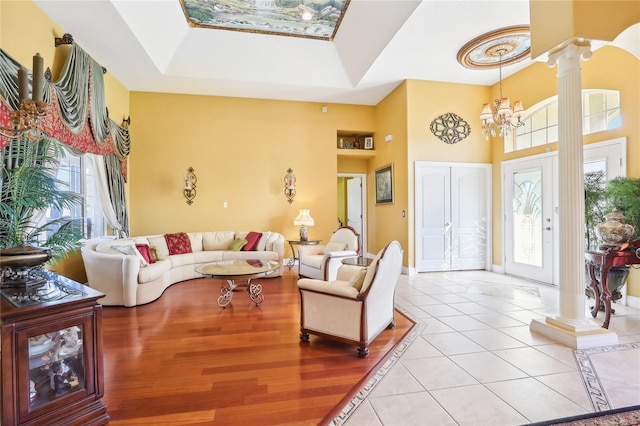 tiled living room with ornate columns, a towering ceiling, and an inviting chandelier