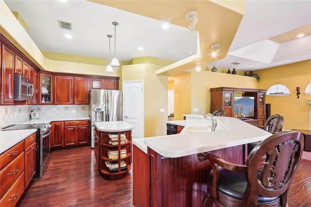 kitchen featuring a kitchen island with sink, sink, decorative light fixtures, appliances with stainless steel finishes, and dark hardwood / wood-style flooring