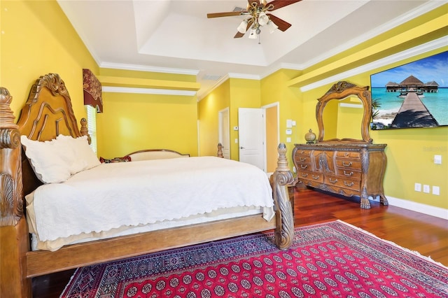 bedroom featuring ornamental molding, dark hardwood / wood-style floors, a tray ceiling, and ceiling fan