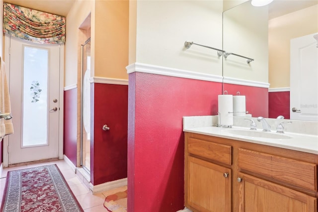 bathroom with a shower with door, tile patterned flooring, and vanity