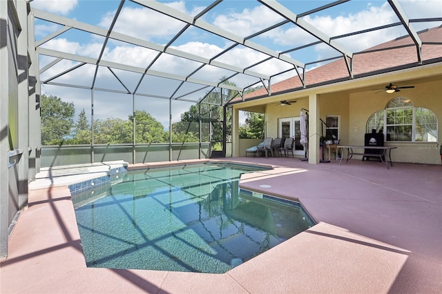 view of pool featuring a patio, glass enclosure, and ceiling fan