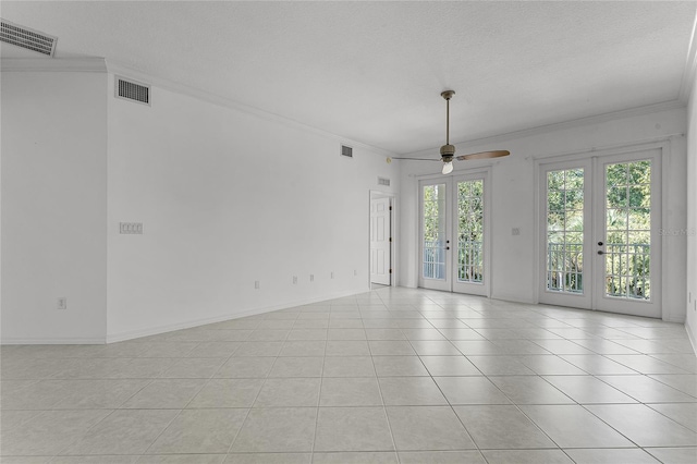 spare room featuring french doors, a textured ceiling, ceiling fan, crown molding, and light tile patterned floors