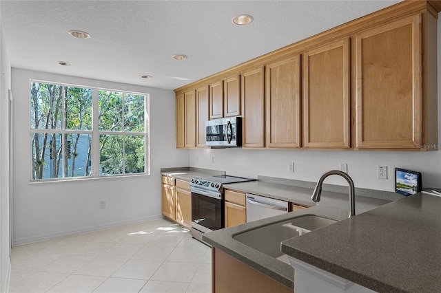 kitchen with sink, kitchen peninsula, a textured ceiling, light tile patterned flooring, and appliances with stainless steel finishes