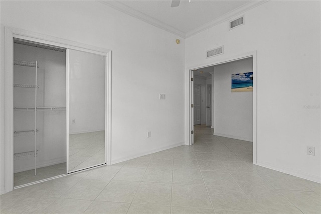 unfurnished bedroom featuring light tile patterned floors, a closet, ornamental molding, and ceiling fan