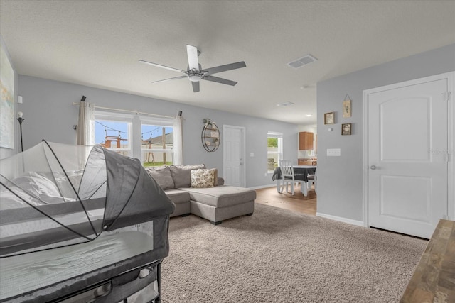 living room featuring a textured ceiling, carpet flooring, and ceiling fan