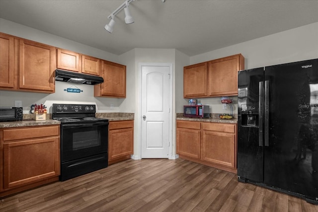 kitchen with black appliances, rail lighting, and dark hardwood / wood-style flooring