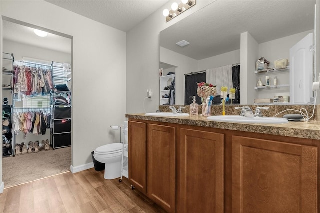 bathroom with vanity, toilet, hardwood / wood-style flooring, and a textured ceiling