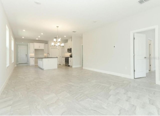 unfurnished living room with sink and an inviting chandelier