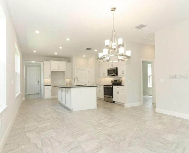 kitchen featuring white cabinets, stainless steel appliances, hanging light fixtures, and an island with sink