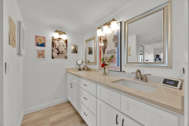 bathroom with hardwood / wood-style flooring, vanity, and a textured ceiling