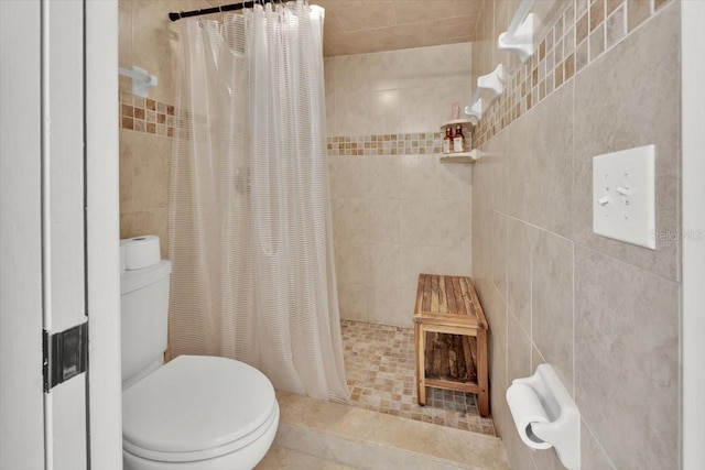 bathroom with a shower with shower curtain, tile patterned floors, toilet, and tile walls