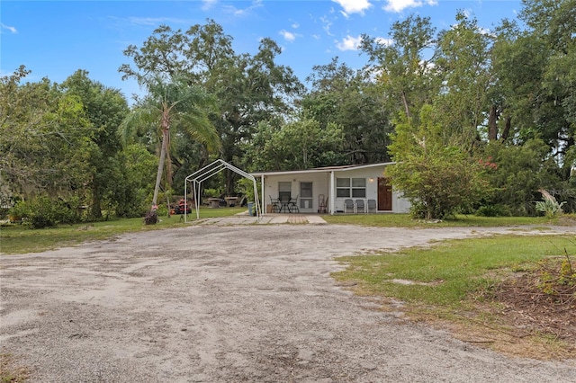 view of front facade with covered porch, a front lawn, and a carport