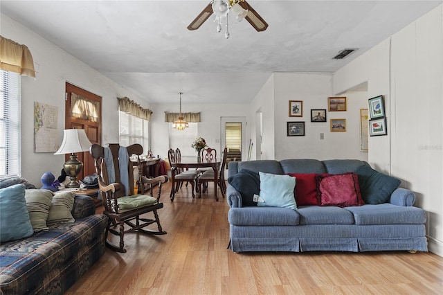 living room with ceiling fan with notable chandelier and light wood-type flooring