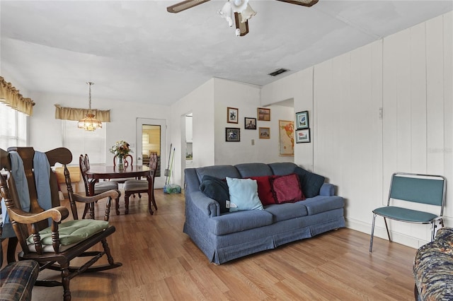 living room with wood-type flooring and ceiling fan with notable chandelier