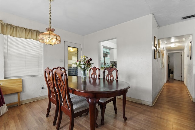 dining area with hardwood / wood-style floors and a chandelier