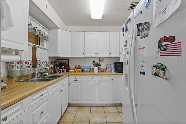 kitchen featuring sink, white cabinets, white refrigerator with ice dispenser, and light tile patterned floors