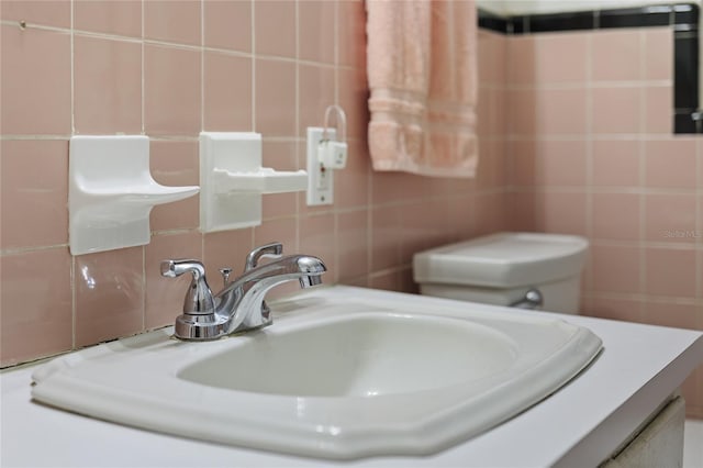 bathroom with vanity, toilet, and tile walls