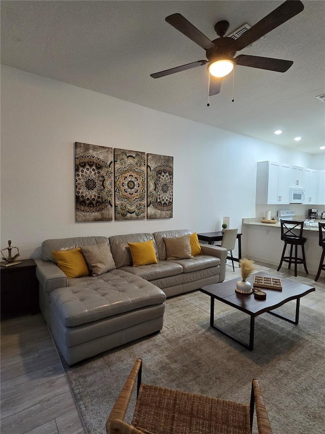 living room featuring a textured ceiling, hardwood / wood-style flooring, and ceiling fan