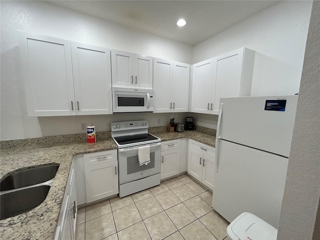 kitchen featuring sink, light tile patterned floors, white cabinetry, light stone counters, and white appliances