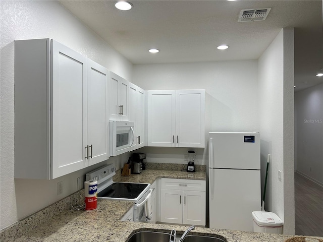 kitchen with sink, white cabinets, wood-type flooring, and white appliances