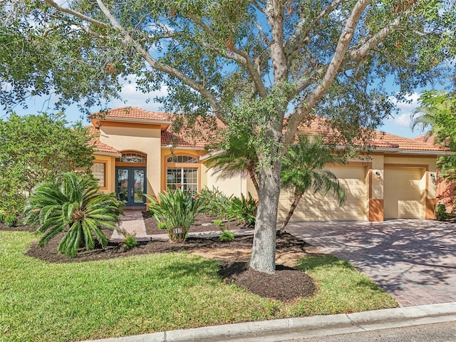 mediterranean / spanish-style house with french doors, a front lawn, and a garage