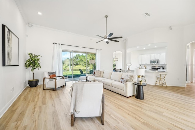 living room with light hardwood / wood-style flooring, ornamental molding, and ceiling fan