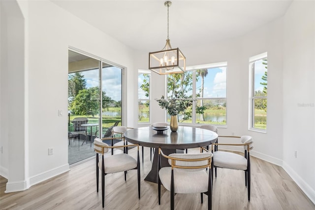 dining area with a chandelier, a water view, light hardwood / wood-style flooring, and plenty of natural light