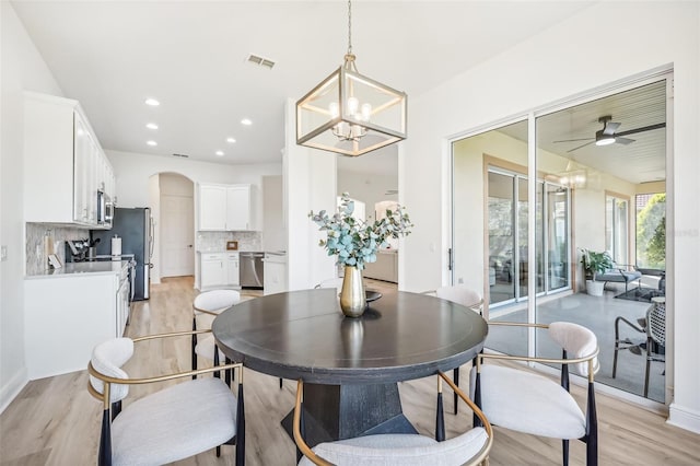 dining space featuring ceiling fan with notable chandelier and light wood-type flooring