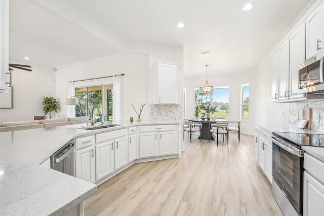 kitchen featuring decorative light fixtures, white cabinetry, sink, and stainless steel appliances