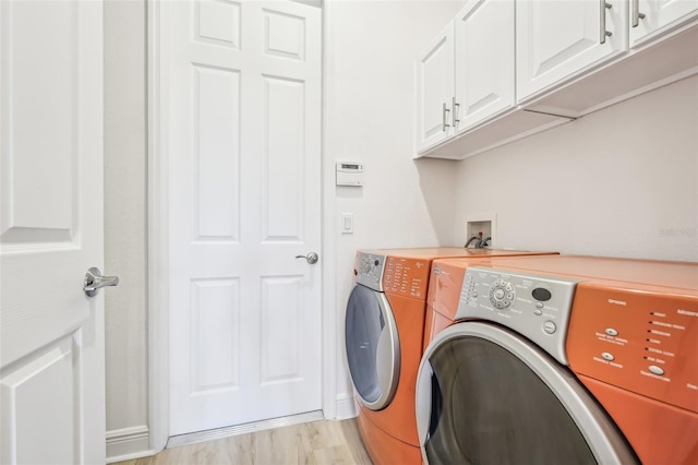 washroom featuring separate washer and dryer, cabinets, and light hardwood / wood-style floors