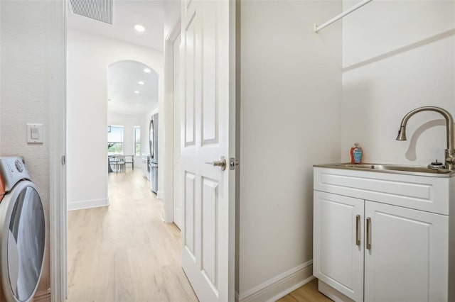 washroom featuring cabinets, sink, light hardwood / wood-style flooring, and washer / dryer