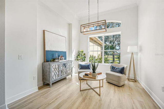 sitting room with light hardwood / wood-style floors, an inviting chandelier, and ornamental molding