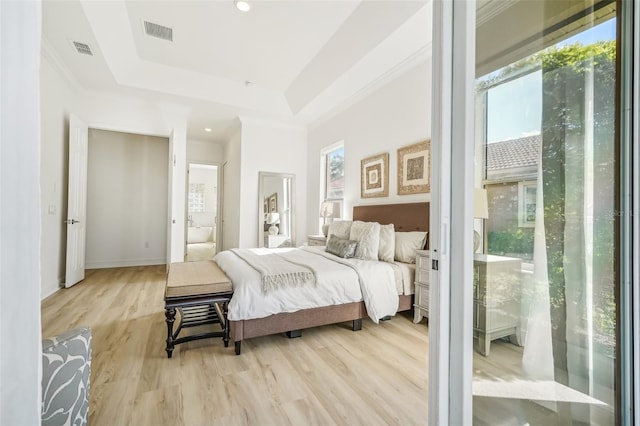 bedroom with ornamental molding, a tray ceiling, multiple windows, and light hardwood / wood-style floors