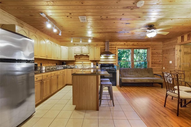 kitchen with stainless steel fridge, a kitchen island, a kitchen breakfast bar, black range, and wall chimney exhaust hood