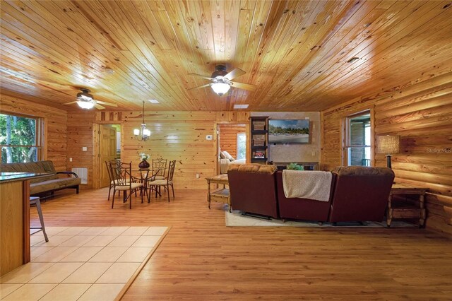 living room with wood ceiling, light wood-type flooring, wooden walls, and ceiling fan