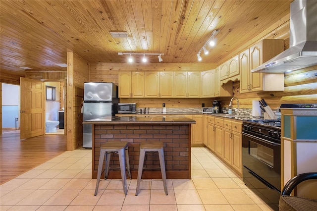 kitchen featuring light brown cabinetry, a center island, rail lighting, stainless steel appliances, and wall chimney exhaust hood