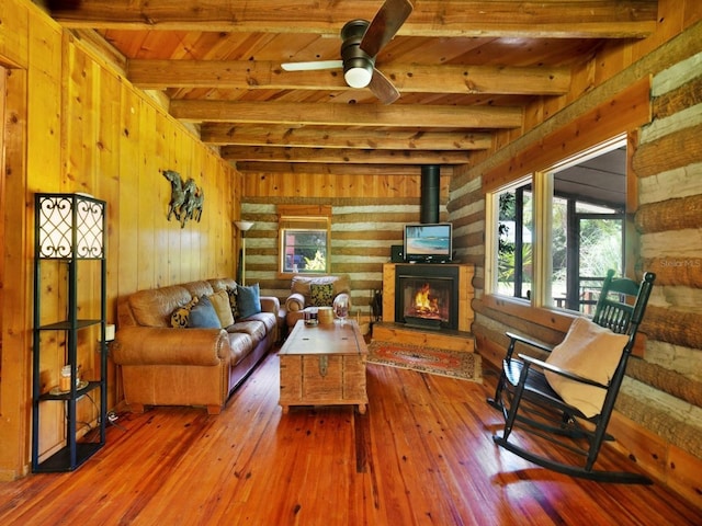 living room with wood walls, wood ceiling, hardwood / wood-style floors, ceiling fan, and beam ceiling