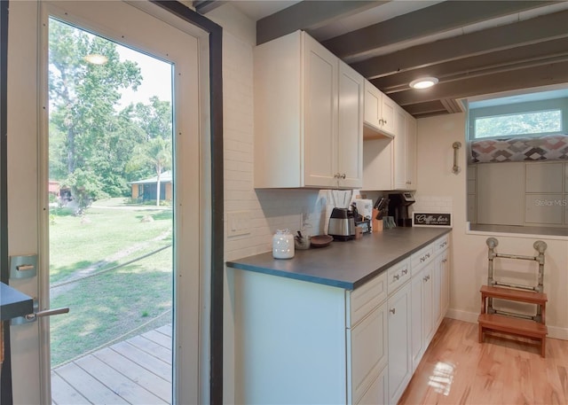 kitchen with decorative backsplash, white cabinets, beamed ceiling, and light hardwood / wood-style floors