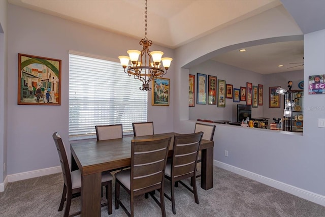 carpeted dining room with ceiling fan with notable chandelier