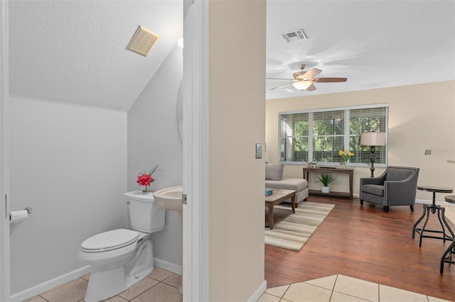 bathroom with toilet, a textured ceiling, wood-type flooring, and ceiling fan