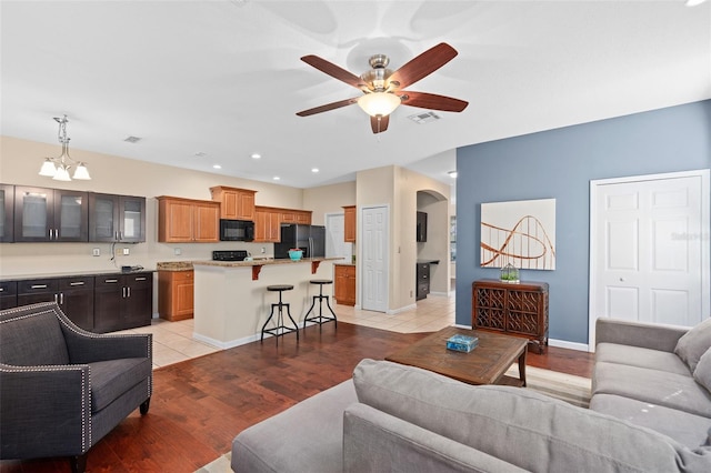 living room featuring light hardwood / wood-style flooring and ceiling fan with notable chandelier