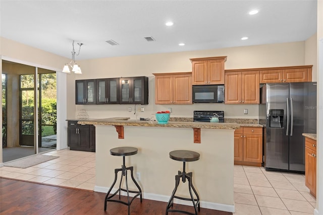 kitchen with light stone countertops, black appliances, a center island, and light wood-type flooring