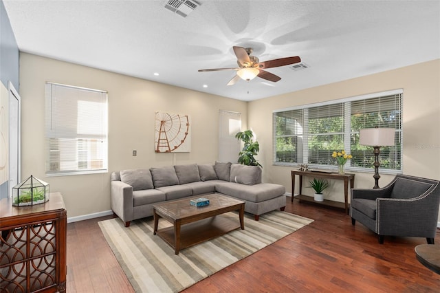 living room featuring dark wood-type flooring, ceiling fan, a healthy amount of sunlight, and a textured ceiling