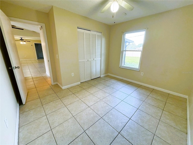 unfurnished bedroom with a closet, light tile patterned floors, and ceiling fan