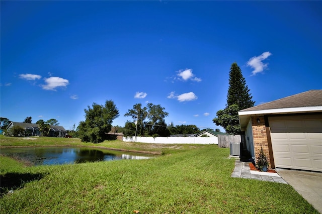 view of yard featuring central AC, a garage, and a water view