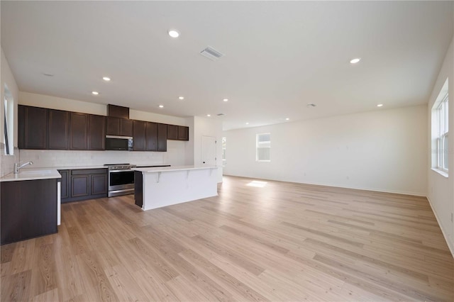 kitchen with a kitchen island, tasteful backsplash, sink, stainless steel appliances, and light wood-type flooring