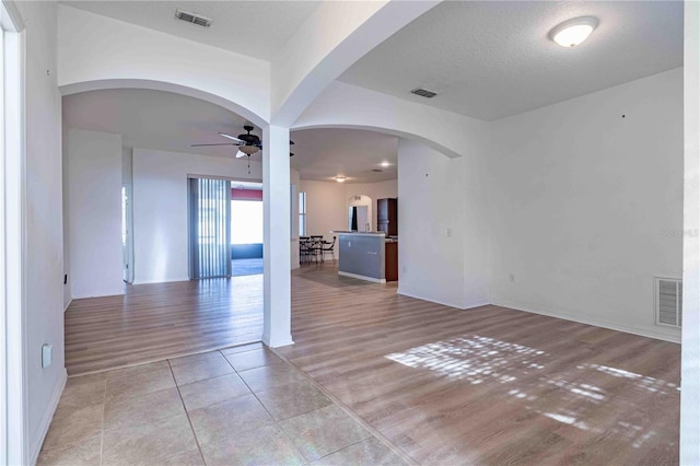 unfurnished room featuring ceiling fan, light wood-type flooring, and a textured ceiling