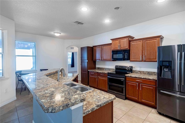 kitchen with a center island with sink, sink, appliances with stainless steel finishes, and a textured ceiling