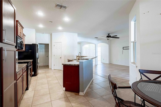 kitchen featuring stainless steel electric range oven, ceiling fan, light tile patterned flooring, and a textured ceiling